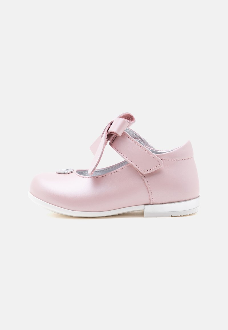 Une chaussure rose pour tout-petit avec une bride à scratch et un nœud décoratif, vue de côté sur fond blanc.