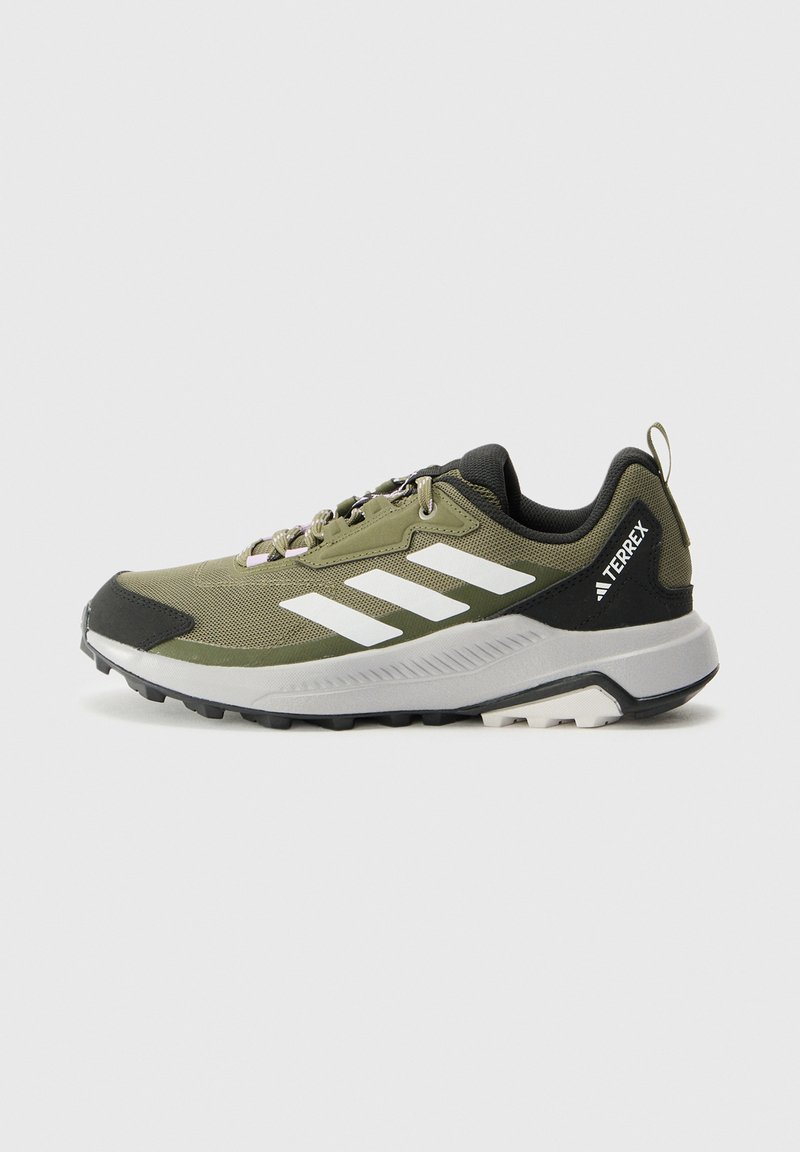 Πράσινο και μαύρο παπούτσι Adidas Terrex για ορεινό τρέξιμο με λευκές ρίγες και ανθεκτική σόλα, εμφανίζεται από το πλάι σε ανοιχτό φόντο.