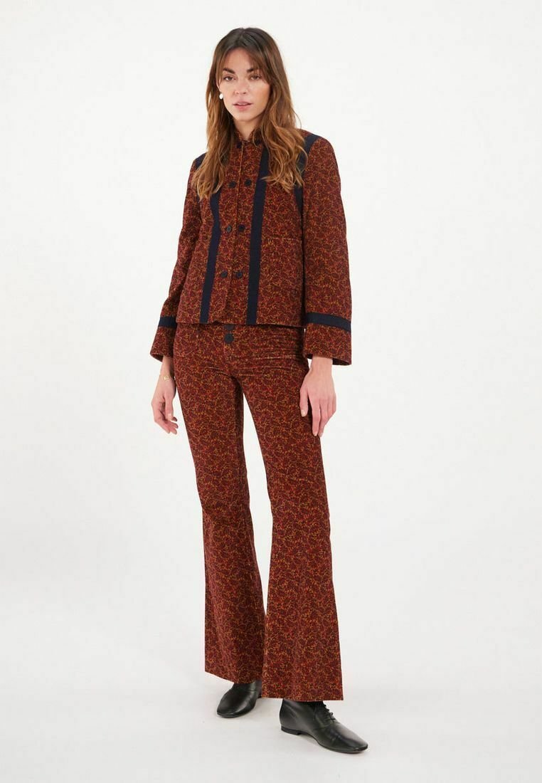 Ensemble deux pièces à motifs rouges comprenant une veste courte avec des accents marine et un pantalon évasé. Le tissu présente une texture et des détails distinctifs.
