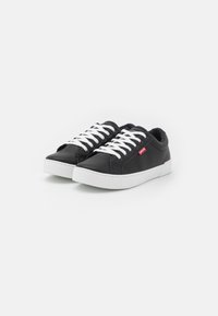 Black synthetic sneakers with white laces, featuring a round toe and a low-profile design. A small red logo is visible on the side.