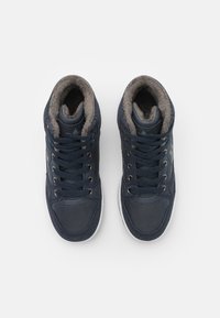 Zapatillas altas de color azul oscuro con parte superior de ante y textil, cuello acolchado, suela de goma blanca y forro de pelaje sintético gris en contraste.