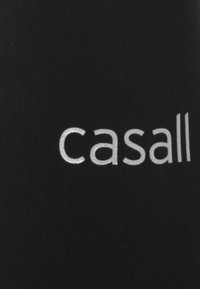 Czarny materiał o gładkiej teksturze ma wyraźnie wyeksponowane srebrne logo "casall" napisane małymi literami.