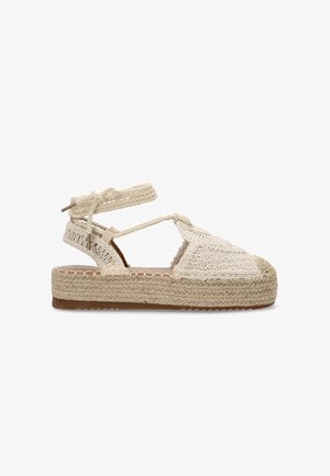 Sandalia espadrille tejida de color beige con correas entrelazadas y una suela de yute trenzado gruesa. En la parte delantera presenta un diseño de punta redondeada texturizada.