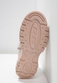 Ljusrosa gummisula med strukturerad yta, som har ett mönstrat däck och det präglade logotyperna "DK Dockers by Golf."