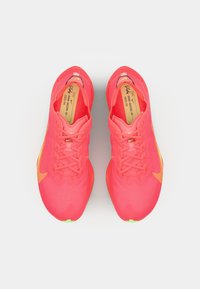 Felroze sportieve schoenen met een gestructureerde bovenkant, vetersluiting en gele accenten. Bevatten een ronde neus en een groene zool.