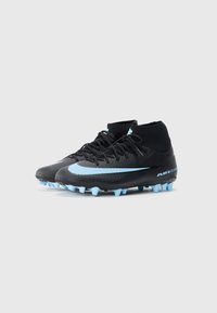 Bottes de soccer montantes noires avec un swoosh Nike bleu clair, des crampons et la marque "Air Zoom" sur un fond blanc.