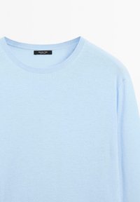 Lichtblauwe gebreide trui met een ronde hals, voorzien van een gladde textuur en lange mouwen. Etiket zichtbaar bij de hals.