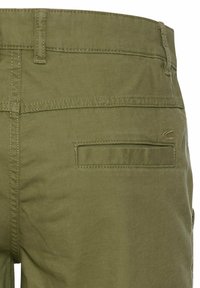 Groene katoenen shorts hebben een rechthoekige achterzak, subtiele gestikte details en een gladde textuur.