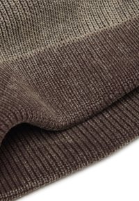 Gebreide stof in bruin en beige tinten heeft een geribbelde structuur. Het artikel vertoont een soepele overgang tussen kleuren bij de naad.