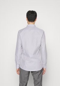 Chemise bleu clair à motifs, manches longues, poignets à boutons et col à pointes écartées, avec un design à carreaux subtil et une texture de tissu lisse.