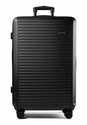 Grande valise rigide noire avec des rainures horizontales, poignée télescopique et quatre roues multidirectionnelles.