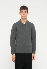 Suéter de lana gris con cuello abotonado, dobladillo y puños acanalados. La tela parece suave con un acabado texturizado.