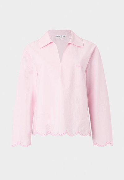 Világos rózsaszín hosszú ujjú blúz nyitott gallérral, hullámos szegélyekkel és finom hímzett részletekkel az alján és a mandzsettán.