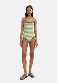 Jednoczęściowy strój kąpielowy w zielono-niebieskie paski z bezrękawym krojem i cienkimi brązowymi ramiączkami. Posiada wysokie wycięcia na nogi i dopasowany fason.