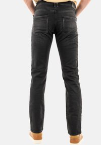 Jeans in denim nero con una vestibilità slim, cinque tasche e dettagli leggermente sbiaditi. Finiti con una vita e indossati con sneakers color sabbia.