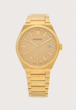Zlaté hodinky Versace s kovovým náramkom, guľatým ciferníkom, hodinovými indexmi v tvare čiarki, zobrazením dátumu na pozícii 3 a logom Medusa na pozícii 12.