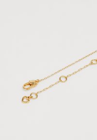 Gold chain necklace featuring round links, a lobster clasp, and a small heart charm. Smooth texture with a shiny finish.