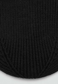 Tessuto nero lavorato a maglia con una texture a coste e un bordo arrotondato, caratterizzato da cuciture fitte e un aspetto morbido.