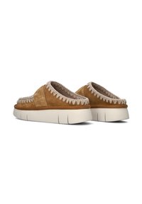 Chaussures à enfiler en daim marron avec une semelle en caoutchouc crème. Dotées de coutures décoratives le long du bord supérieur et d'un intérieur rembourré.