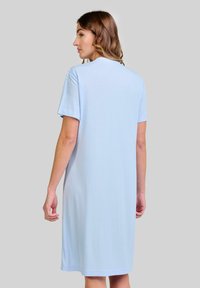 Vestido de manga corta azul claro, hecho de una tela suave, con un corte relajado y una longitud hasta la rodilla, que presenta una textura simple y lisa.