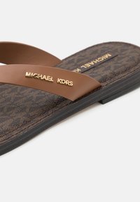 Infradito marroni con fasce decorate e una soletta marrone testurizzata. Presenta il marchio oro "MICHAEL KORS" sulla fascia.