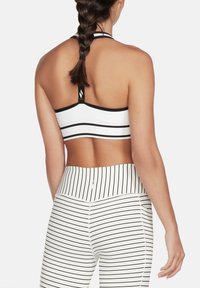 Sujetador deportivo de rayas blancas y negras con diseño de espalda nadadora y banda elástica, combinado con leggings a la cintura de rayas a juego.