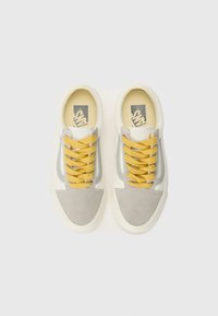Canvas sneakers in cream with gray suede accents and yellow laces. Features a rubber sole and round toe design.