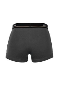 Schwarze Boxer-Briefs aus glattem Baumwollmaterial, mit einem schwarzen Bündchen mit Logo und einer goldenen Akzentlinie, entworfen für eine enganliegende Passform.