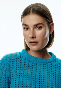 Helles blauer Strickpullover mit einem offenen Mesh-Design, rundem Halsausschnitt und kurzen Ärmeln mit strukturiertem Finish.