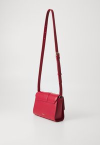 Borsa a spalla in pelle rossa con un design strutturato, parte superiore piatta e tracolla regolabile. Caratterizzata da una texture liscia e un discreto dettaglio del logo sulla parte frontale.