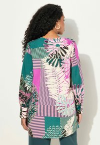 Blusa multicolore con motivi floreali e geometrici; presenta maniche lunghe, una vestibilità ampia e un vivace mix di teal, rosa e crema.