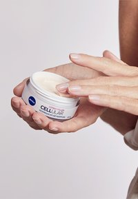 Nivea Cellular Expert Filler, white cream in a cylindrical jar, held in a hand. Notable smooth texture and pale color, with a blue logo.
