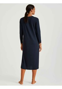 Camicia da notte blu navy realizzata in tessuto morbido, con maniche lunghe e dettagli in pizzo sui polsini, lunghezza ginocchio e silhouette dritta.