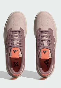 Sneaker con una toma superiore in tela rosa, accenti viola scuro e una suola in gomma di texture. Caratterizzano una linguetta color pesca e dettagli bianchi del logo.