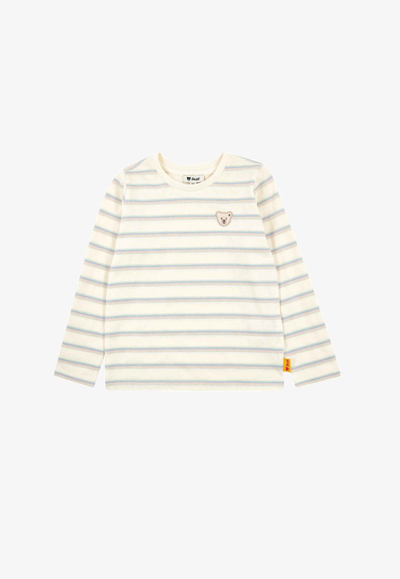 Camisa de manga larga color crema con rayas horizontales en tonos pastel. Presenta un pequeño parche con forma de oso en el lado izquierdo del pecho y una etiqueta de marca amarilla en un lateral.