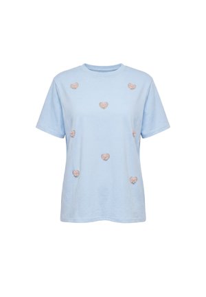 Lyseblå kortærmet T-shirt med spredte lyserøde broderede hjertepatches på forsiden, vist på en ensfarvet hvid baggrund.