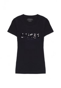 T-shirt in cotone nero con scollo a V e maniche corte. Presenta il logo "GUESS" in paillettes con un effetto luccicante. Design semplice e aderente.