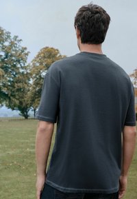 Donkergrijze katoenen T-shirt met korte mouwen en een ronde halslijn, met een relaxte pasvorm en subtiele stiksels op de zomen.
