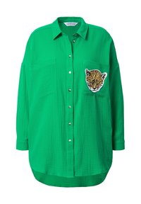 Zelená košile na knoflíky s texturovanou tkaninou. Obsahuje dvě přední kapsy a vyšívanou tvář leopardí na levé kapse.
