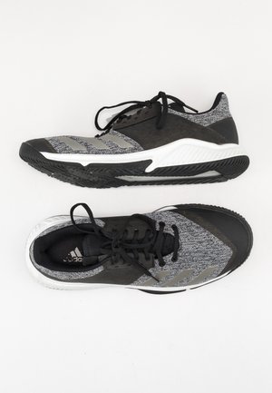 Paar schwarze und graue Adidas Sportschuhe mit weißen Sohlen, eines zeigt die Seitenansicht und das andere die Draufsicht auf weißem Hintergrund.