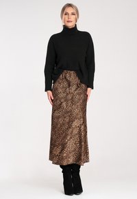 Czarny sweter z golfem z dzianiny w połączeniu z brązową spódnicą maxi w leopardzie. Całość uzupełniają czarne kozaki do kolan.