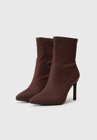 Brune stof ankelstøvler med spids tå, slank stiletto-hæl og strækbart overdel-design. Glat tekstur uden synlig hardware.