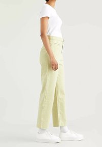 Pantalon à carreaux vichy vert clair et blanc avec taille haute, poches latérales, jambe droite et coupe décontractée, assorti à des baskets blanches.
