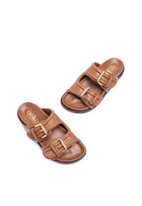 Brown leather sandals featuring two adjustable straps with gold-tone buckles, open-toe design, and a smooth textured insole.