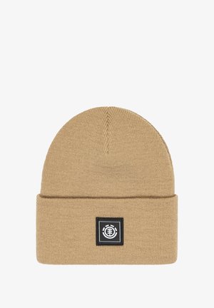 Gorro de punto beige con vuelta, que presenta un parche de logo cuadrado negro. El material parece suave y texturizado, con un diseño de corona sin costuras.