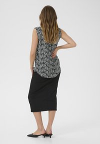 Haut sans manches noir avec des rayures verticales blanches, associé à une jupe noire à hauteur du genou, mettant en avant une texture lisse et un design simple.