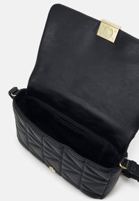 Sac en cuir noir avec quincaillerie dorée, motif matelassé à l'extérieur, design robuste et intérieur spacieux. Bandoulière ajustable incluse.