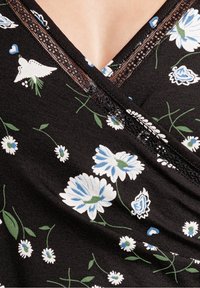 Czarna tkanina z niebieskim i białym wzorem kwiatowym oraz zielonymi łodygami, z dekoltem w kształcie litery V i czarną koronką.