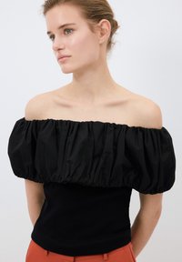 Top nero off-the-shoulder con maniche a sbuffo, caratterizzato da una texture arricciata, corpetto nero aderente e una finitura in cotone morbido.