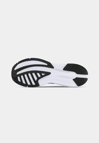 Zwart-witte sportschoen zool met getextureerd rubber voor grip, met een gebogen ontwerp en meerdere groeven voor flexibiliteit.